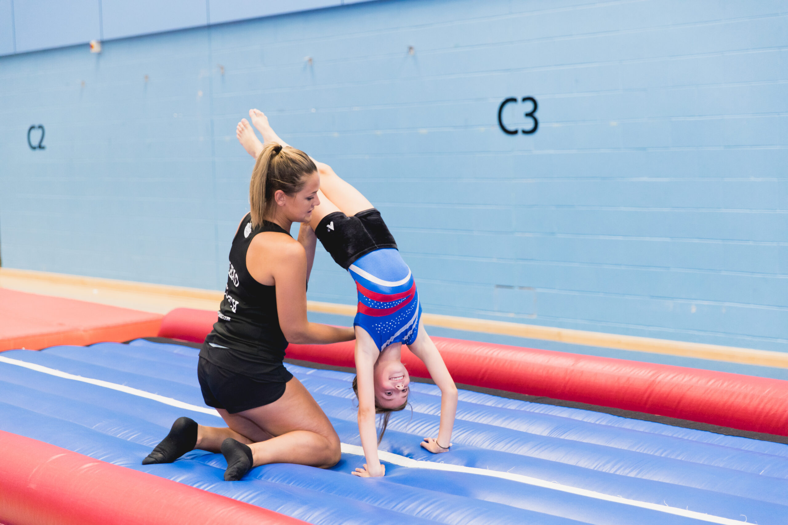 Flair gymnastics coach supports child safely on the air track