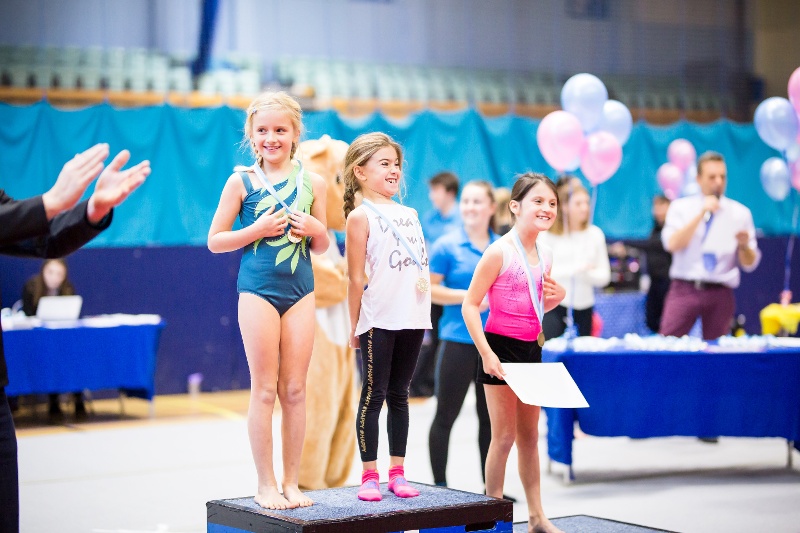 Excited children winning gymnastics medals at the Flair Championships
